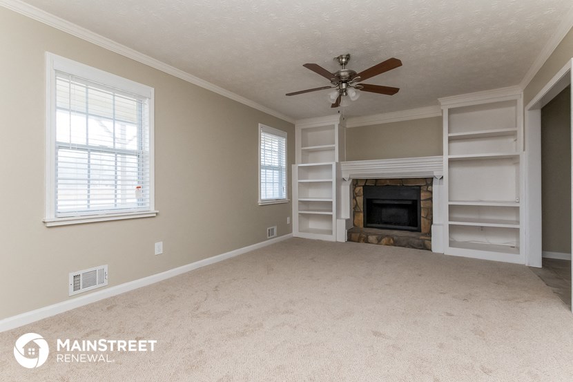 an empty living room with a ceiling fan and a fireplace
