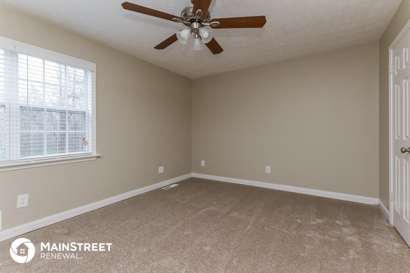 the living room of an empty home with a ceiling fan