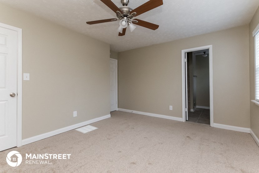 an empty living room with a ceiling fan and a door to a closet