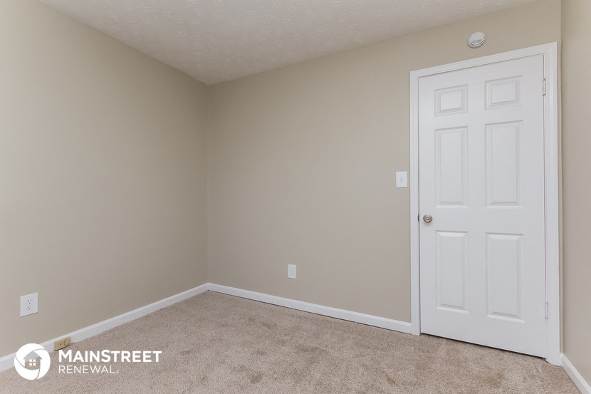a bedroom with a white door and a carpeted floor