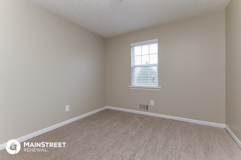 a bedroom with a window and a carpeted floor