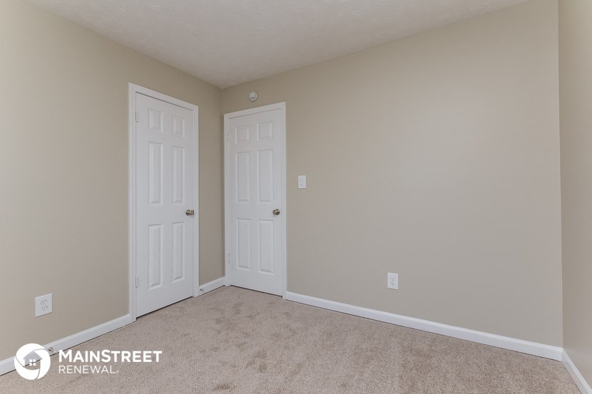 a bedroom with two doors and a carpeted floor