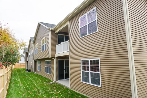 A residential building with a brown siding and a green lawn in front.