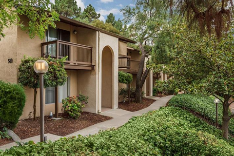 an apartment building with trees and a sidewalk