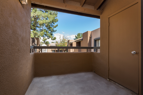 A view from inside a room looking out through a window at a courtyard with trees and buildings.