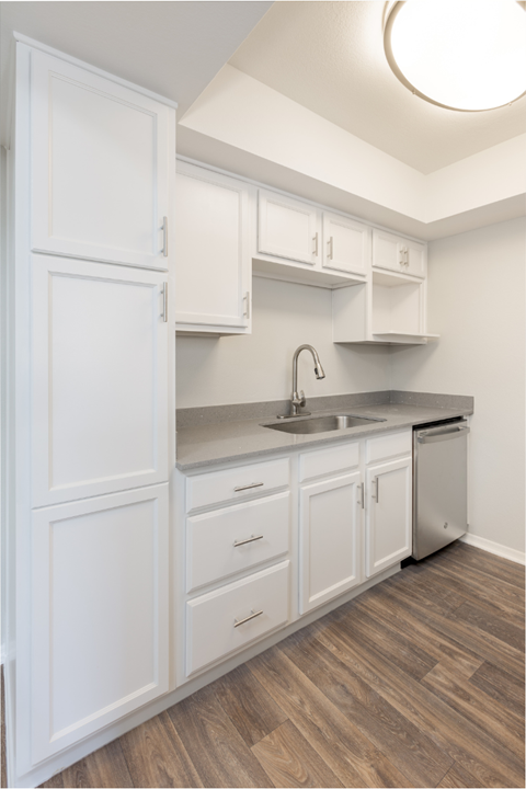 A kitchen with white cabinets and a wooden floor.