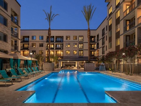 A large swimming pool in front of a building with palm trees.