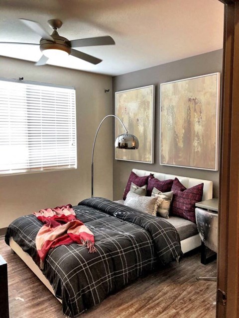 A bedroom with a bed covered in a plaid comforter and pillows.