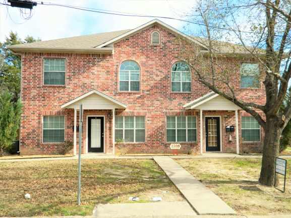 a brick house with a sidewalk in front of it