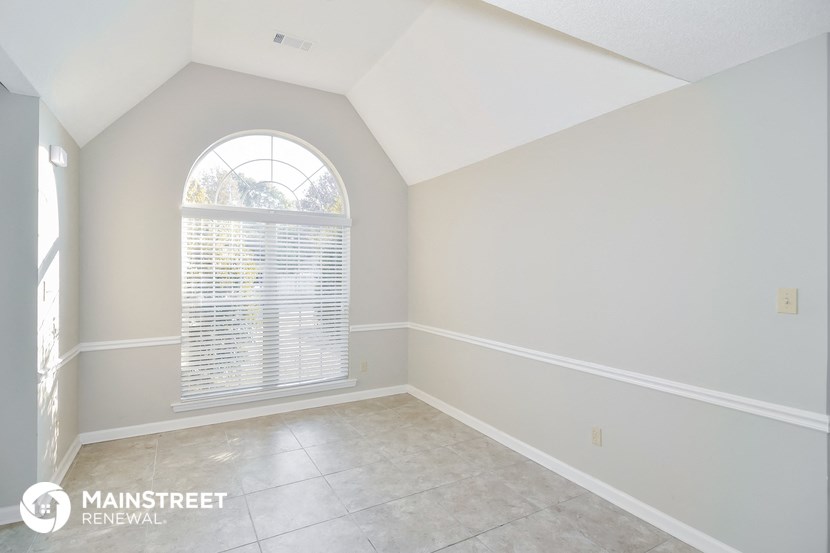 an empty living room with a large window and white walls