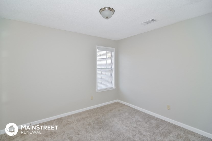 the spacious living room with carpet and window