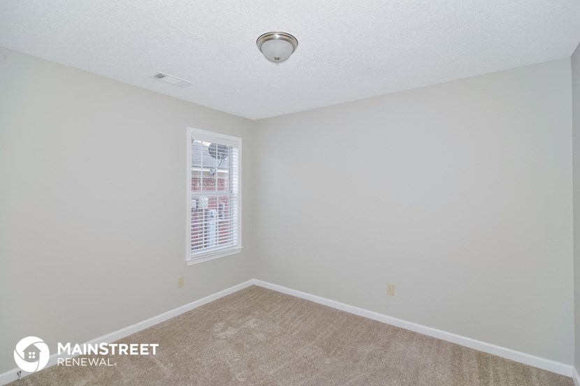 the spacious living room of this manufactured home has white walls and beige carpet
