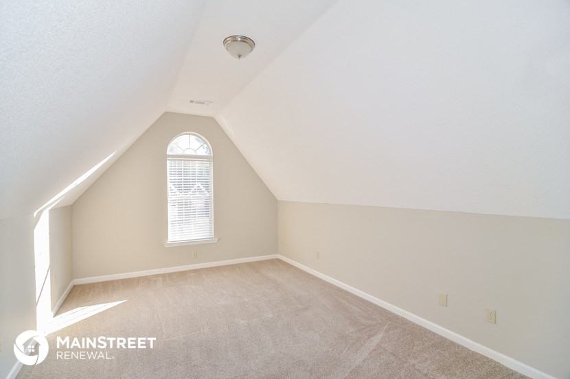 the attic of a home with a carpeted floor and a window