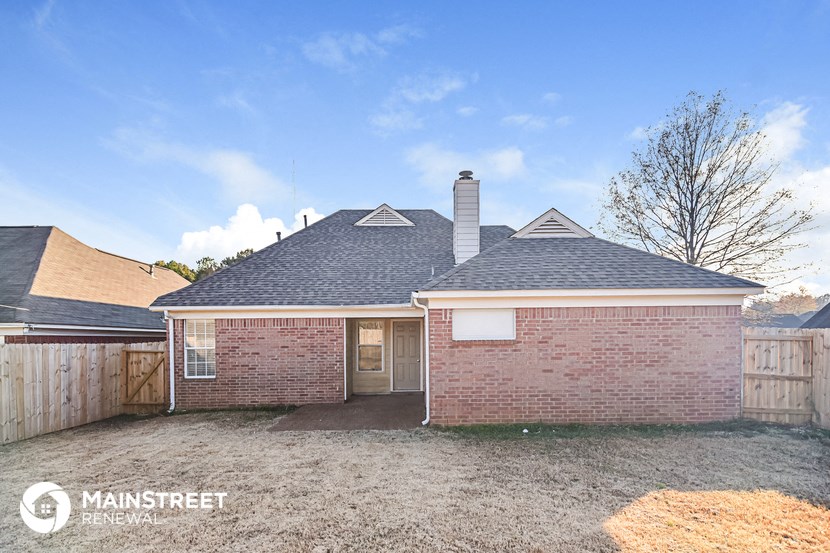 the front of a brick house with a yard and a fence