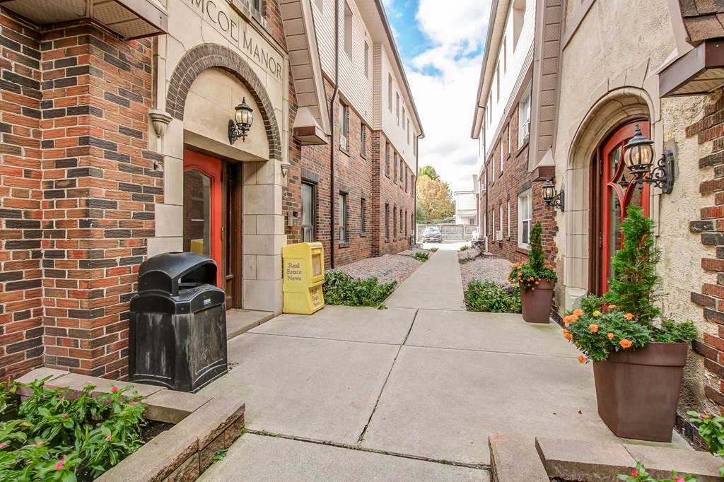A narrow alley with brick buildings and a red door.
