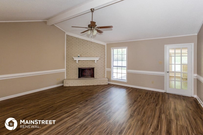 an empty living room with a fireplace and a ceiling fan