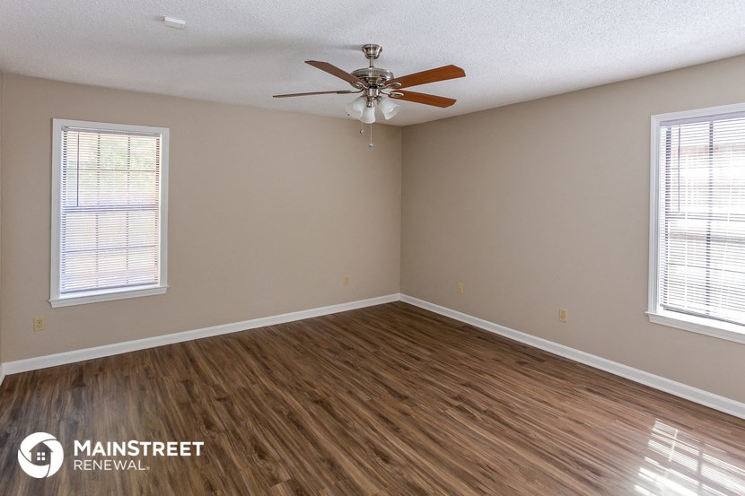 the living room of a home with wood flooring and a ceiling fan