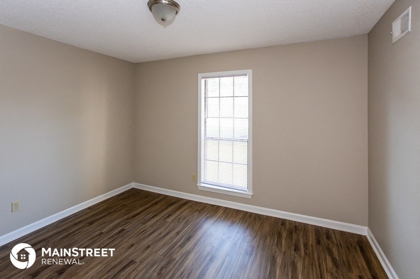 the spacious living room with hardwood flooring and window