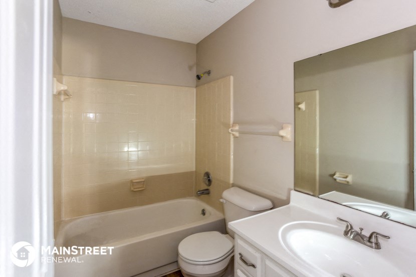a white bathroom with a tub and a sink and a mirror