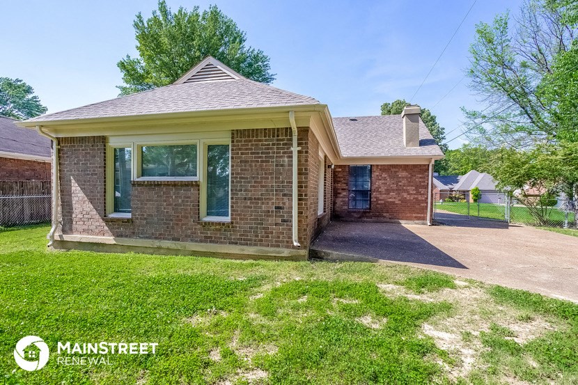 the front of a brick house with a driveway and grass