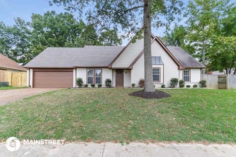 the front of a white house with a lawn and a tree