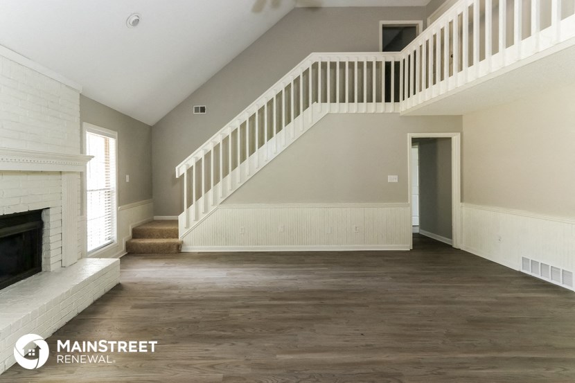 an empty living room with a staircase and a fireplace
