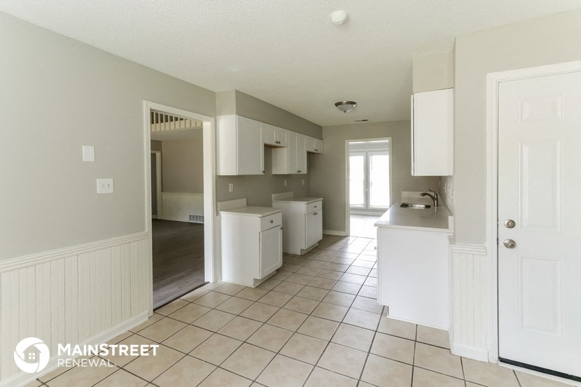 an open kitchen with white cabinets and a tiled floor