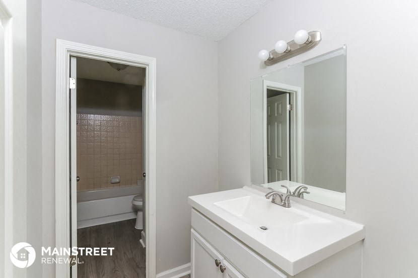 a bathroom with a white sink and a mirror and a tub