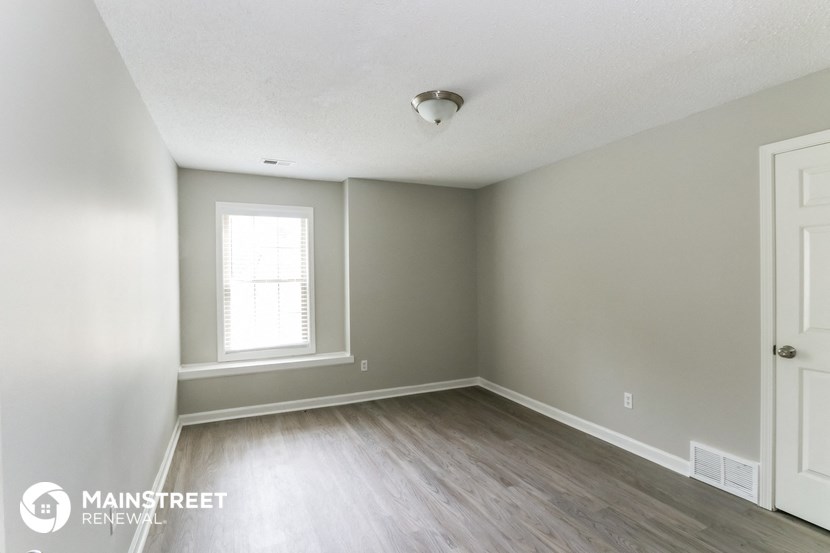 an empty room with wood flooring and a window
