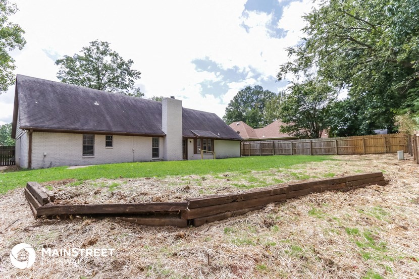 a yard with a fence and a house in the background