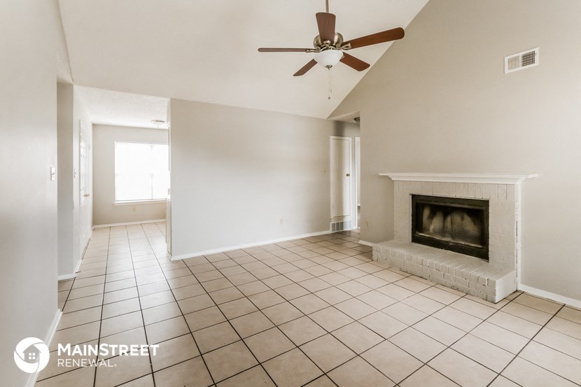an empty living room with a fireplace and a ceiling fan