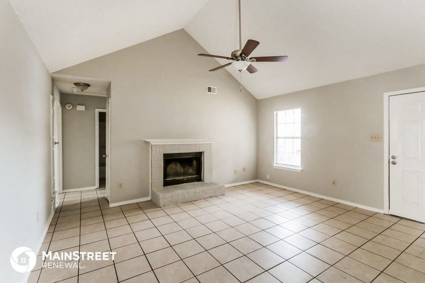 an empty living room with a fireplace and a ceiling fan