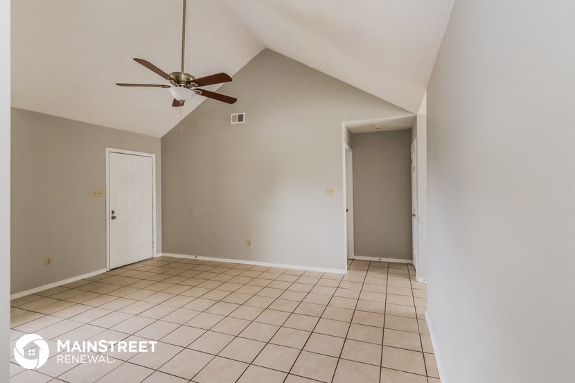 an empty living room with a ceiling fan and tiled floor