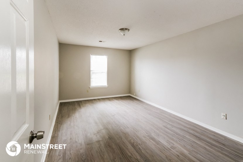 the spacious living room with wood flooring and white walls