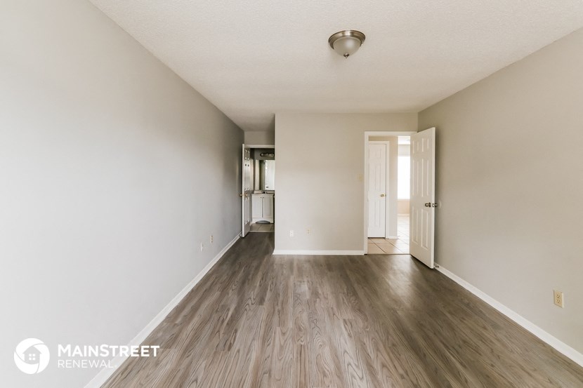 the spacious living room with wood flooring and white walls