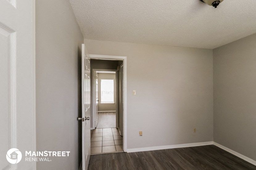 the living room of an apartment with a door to the hallway