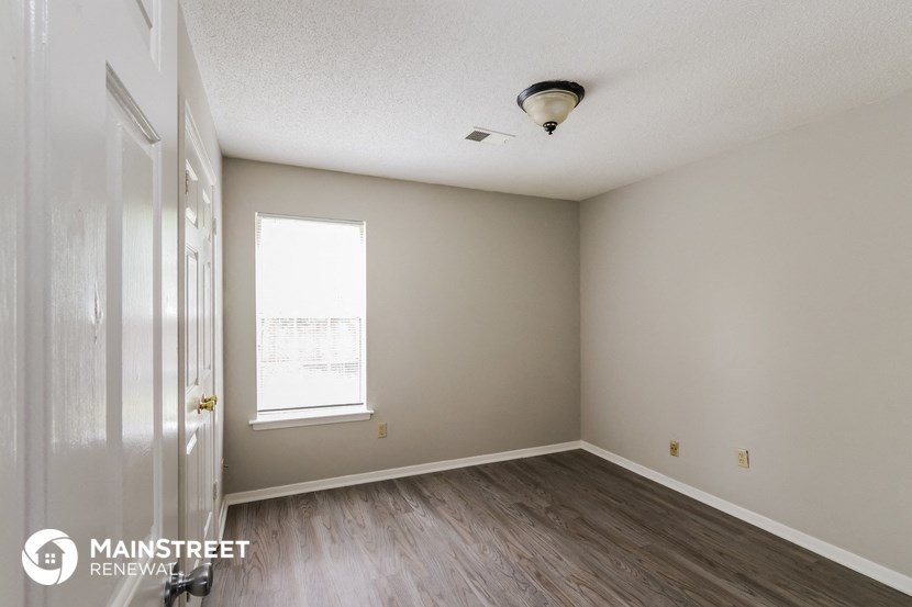 the interior of an empty room with wood flooring and a window