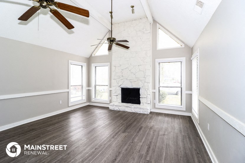 a living room with a fireplace and two ceiling fans