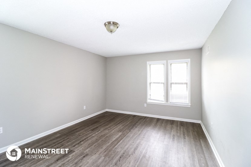 the spacious living room with wood flooring and white walls