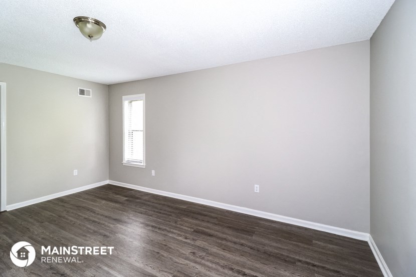 the spacious living room with wood flooring and white walls