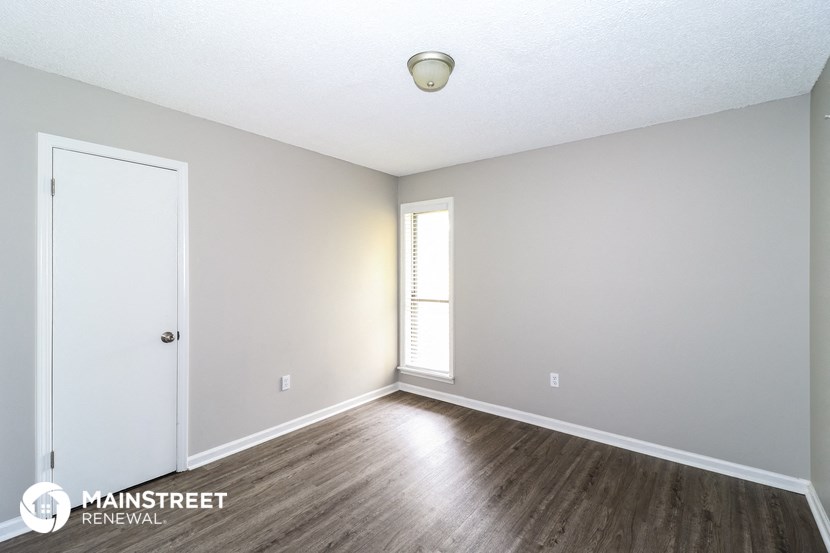 the spacious living room with wood flooring and white walls