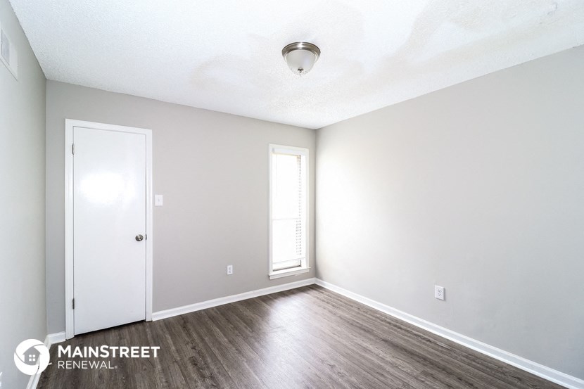 the spacious living room with wood flooring and white walls