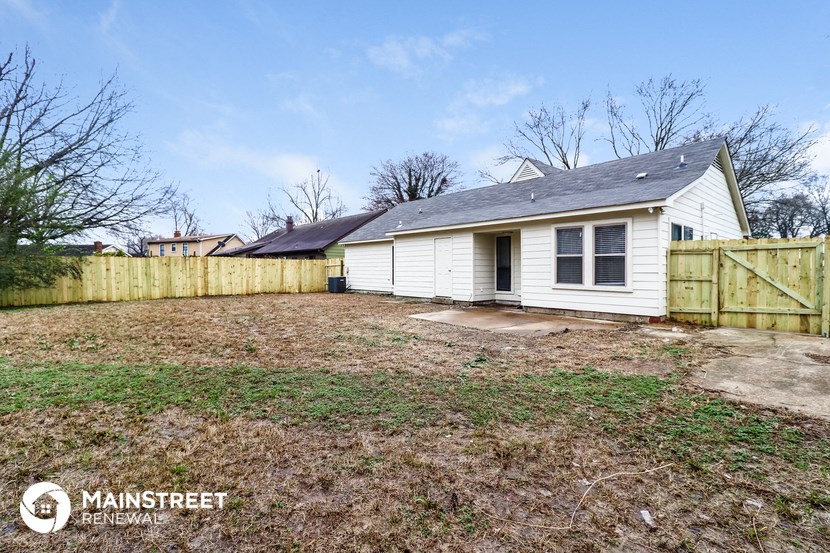 a backyard with a small white house and a wooden fence