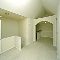 an empty living room with an arched doorway and white walls