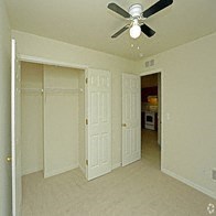 an empty living room with a ceiling fan and a closet