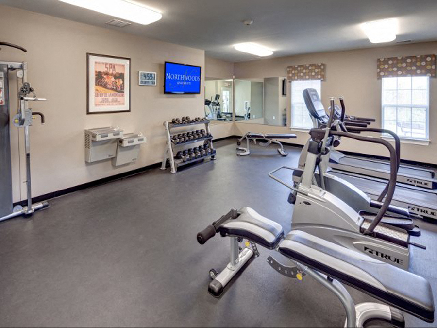 a gym with cardio equipment and a tv on the wall