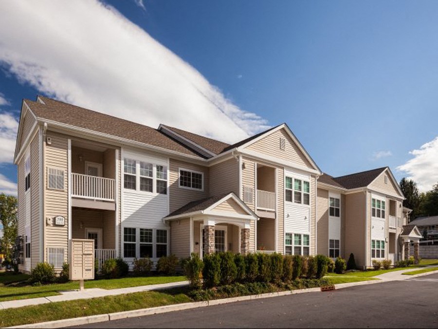 a row of apartment buildings on a street with grass
