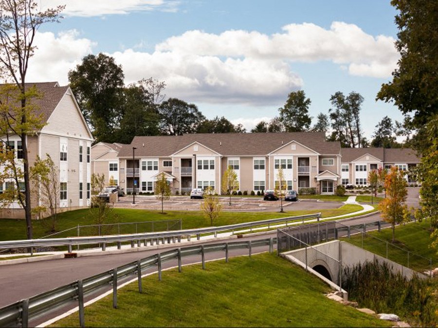an exterior view of an apartment complex with a road and a bridge