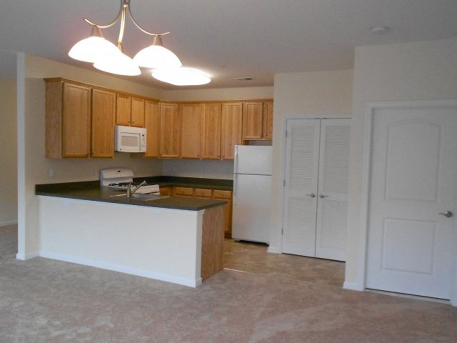 an empty kitchen with white appliances and wooden cabinets