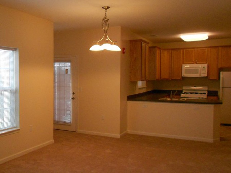 an empty living room and kitchen with a microwave and a sink